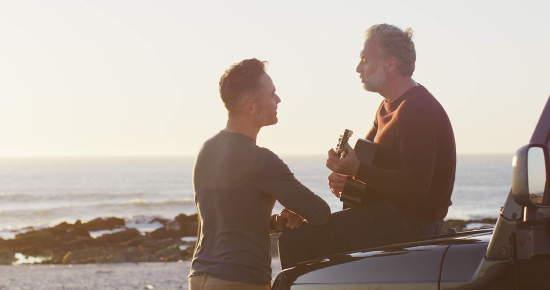 Mature Couple Enjoying Guitar Music by Ocean During Sunset - Free Images, Stock Photos and Pictures on Pikwizard.com