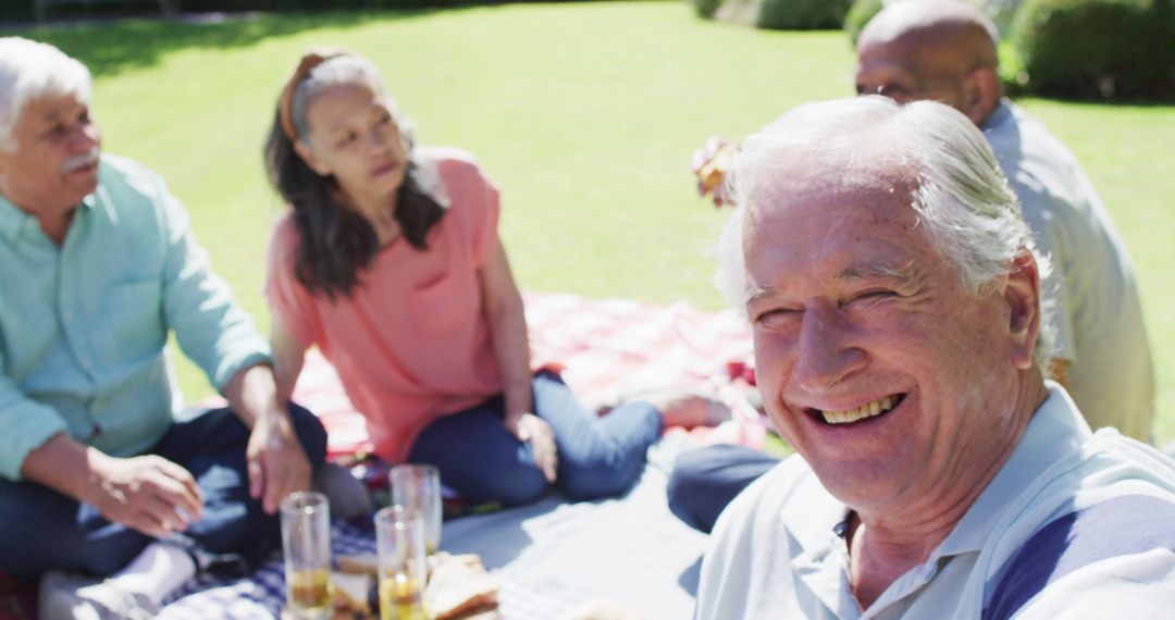 Smiling Elderly Man Enjoying Picnic with Friends in Park - Free Images, Stock Photos and Pictures on Pikwizard.com