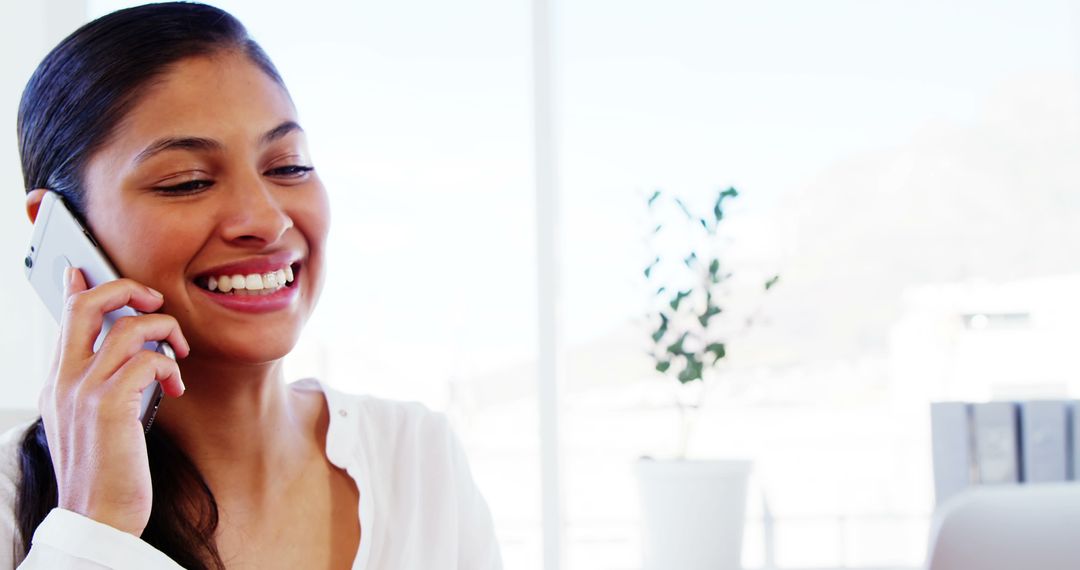 Smiling Woman Talking on Phone in Bright Office
