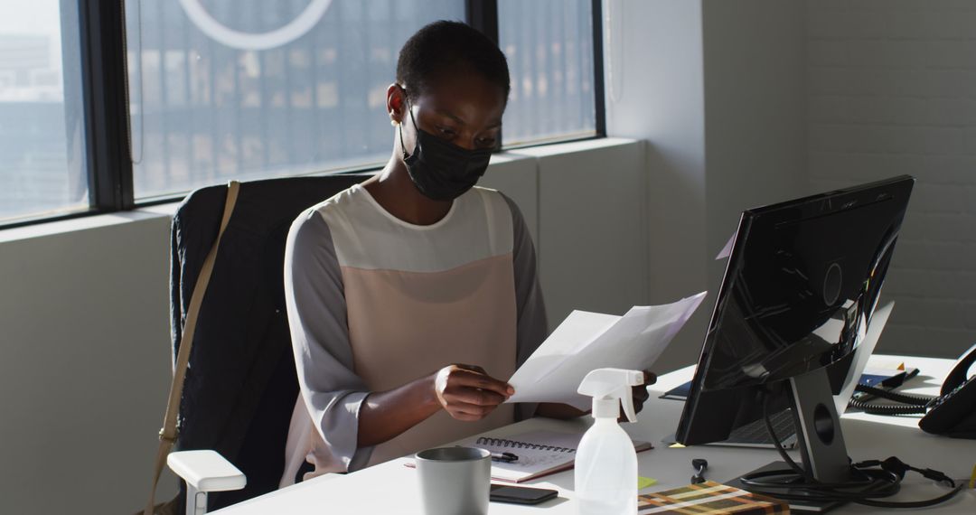 Businesswoman Wearing Mask Working at Desk in Modern Office - Free Images, Stock Photos and Pictures on Pikwizard.com