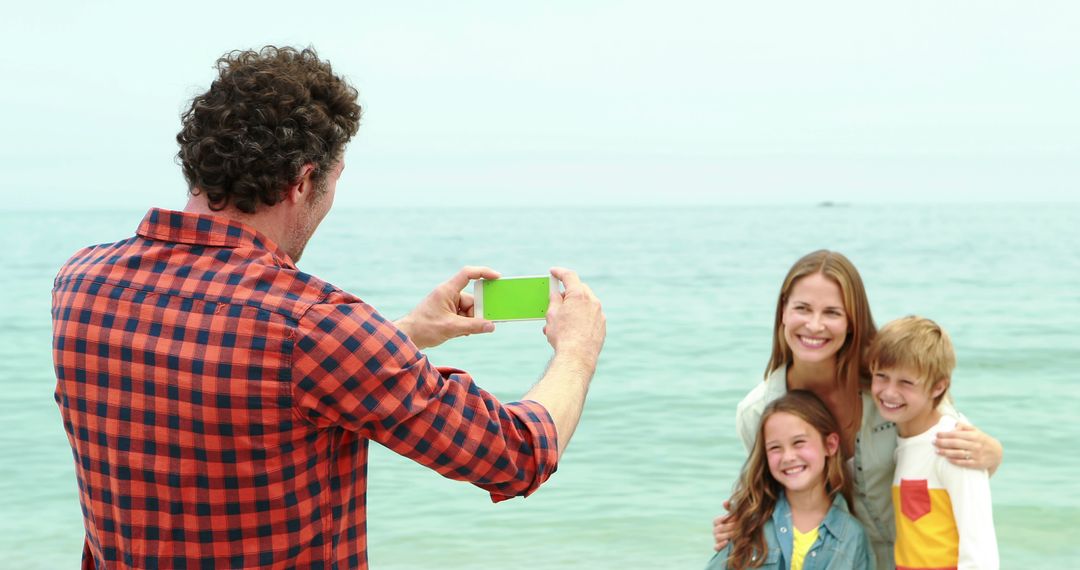 Father taking photo of smiling family at beach - Free Images, Stock Photos and Pictures on Pikwizard.com