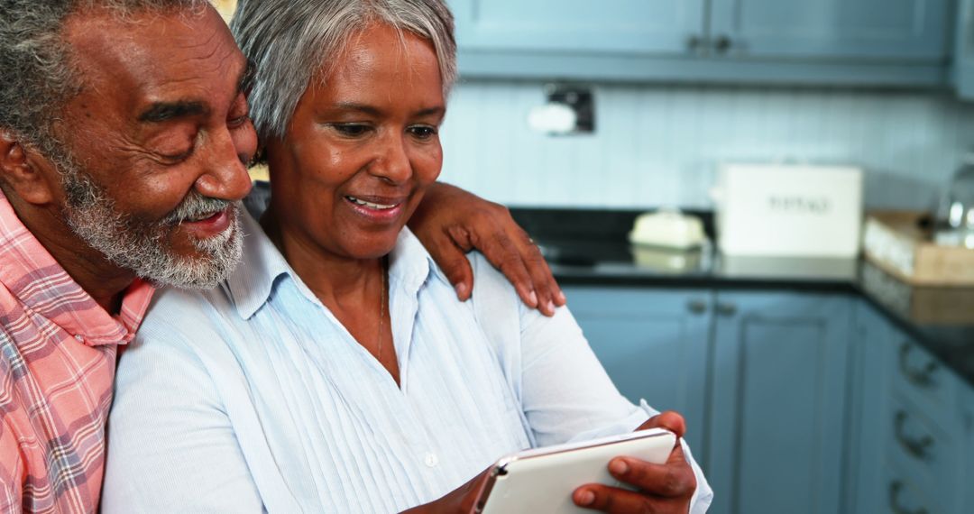 Happy Senior Couple Using Digital Tablet Together in Kitchen