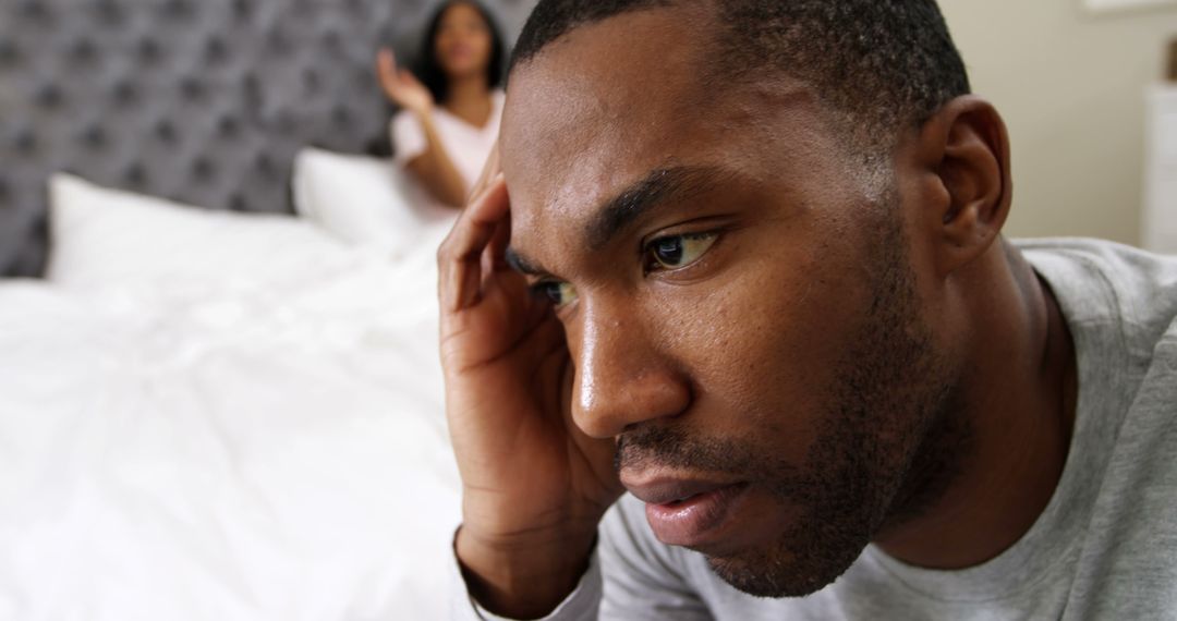 Worried African American Man Sitting on Bed during Relationship Disagreement - Free Images, Stock Photos and Pictures on Pikwizard.com