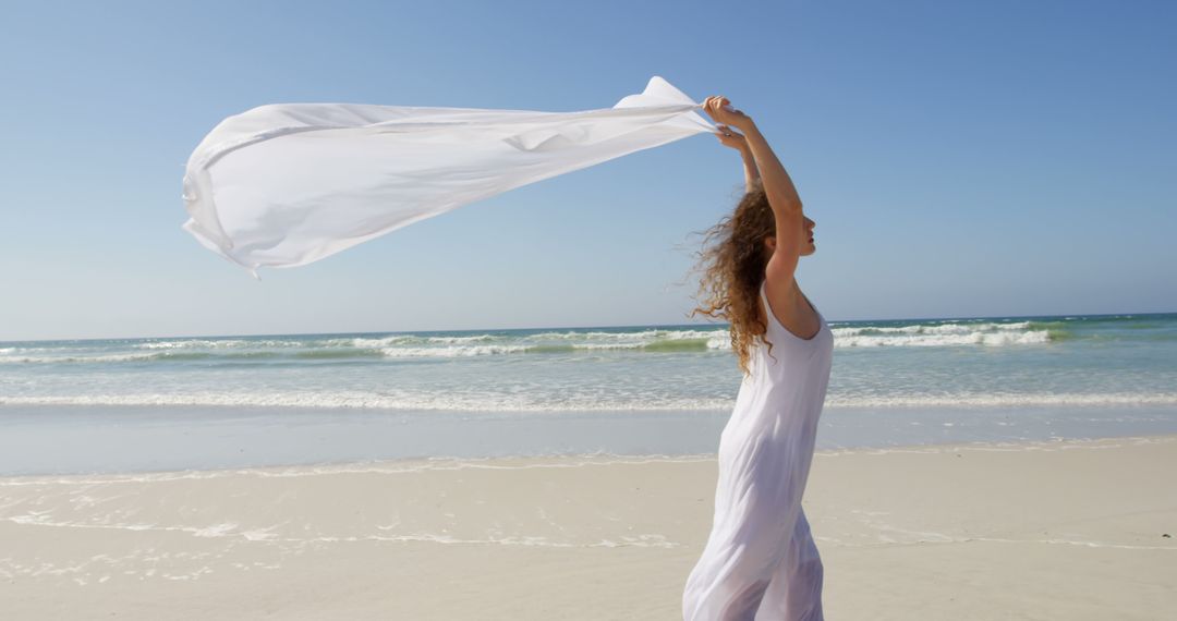 Woman Holding White Scarf by Ocean on Sunny Day - Free Images, Stock Photos and Pictures on Pikwizard.com