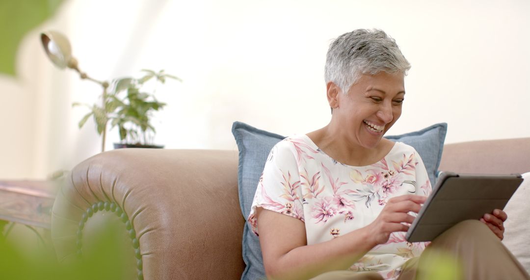 Happy Senior Woman Relaxing on Couch Using Tablet