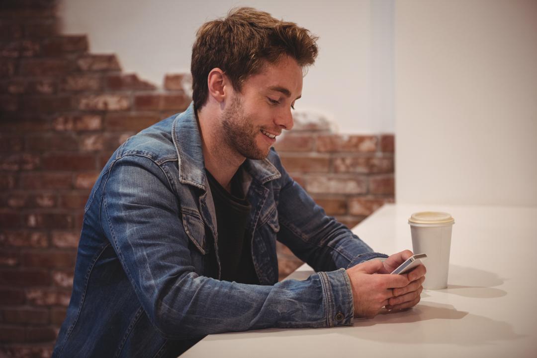 Image of a man using his mobile phone at a table and smiling - Find a way to get feedback from your audience - Image