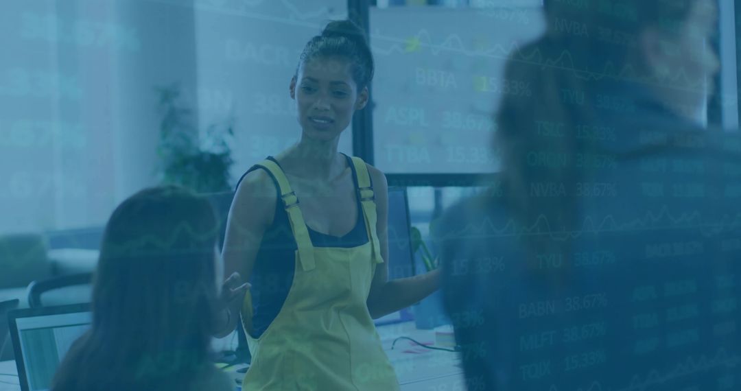 Female Team Leader Explaining Project in Open Office with Screens and Stock Charts