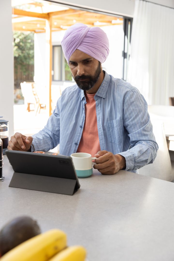 Indian Man with Tablet in Minimalistic Kitchen Setting