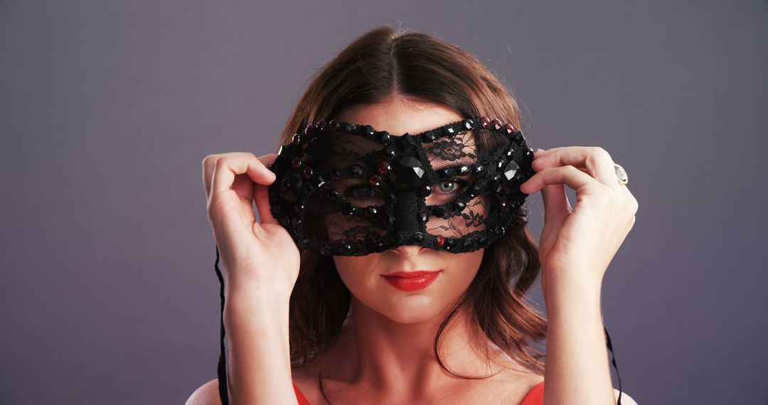A young Caucasian woman holds a black lace mask in front of her eyes, with copy space - Free Images, Stock Photos and Pictures on Pikwizard.com