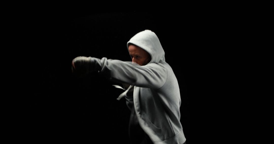 Boxer in Action with Hoodie, Fierce Punch on Black Background - Free Images, Stock Photos and Pictures on Pikwizard.com