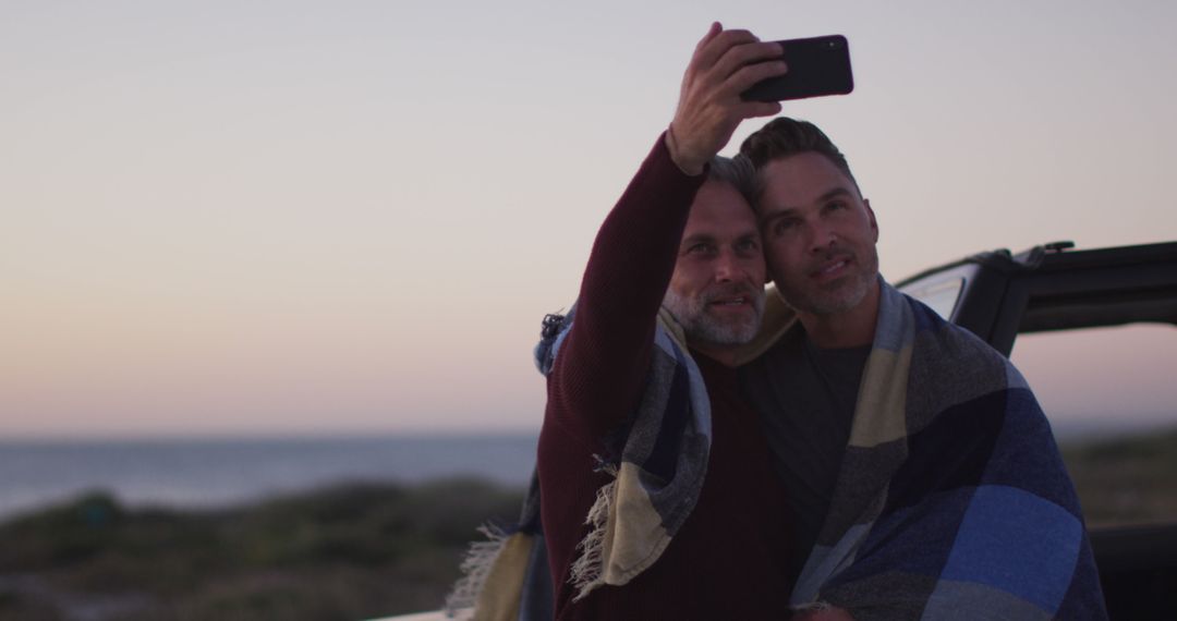 A joyful gay couple enjoys a sunset beach selfie during their summer road trip. - Free Images, Stock Photos and Pictures on Pikwizard.com