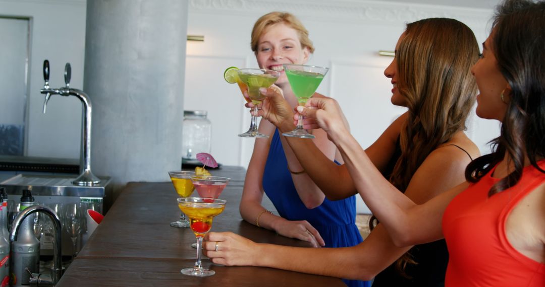 Women Toasting Colorful Cocktails at Bar Counter