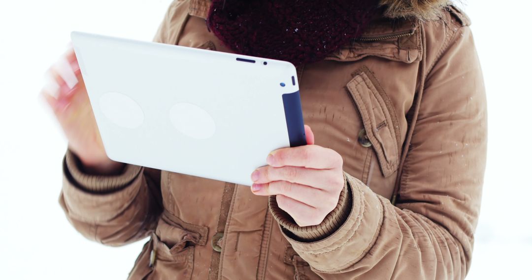 Person Using Tablet in Winter Clothing Outdoors - Free Images, Stock Photos and Pictures on Pikwizard.com