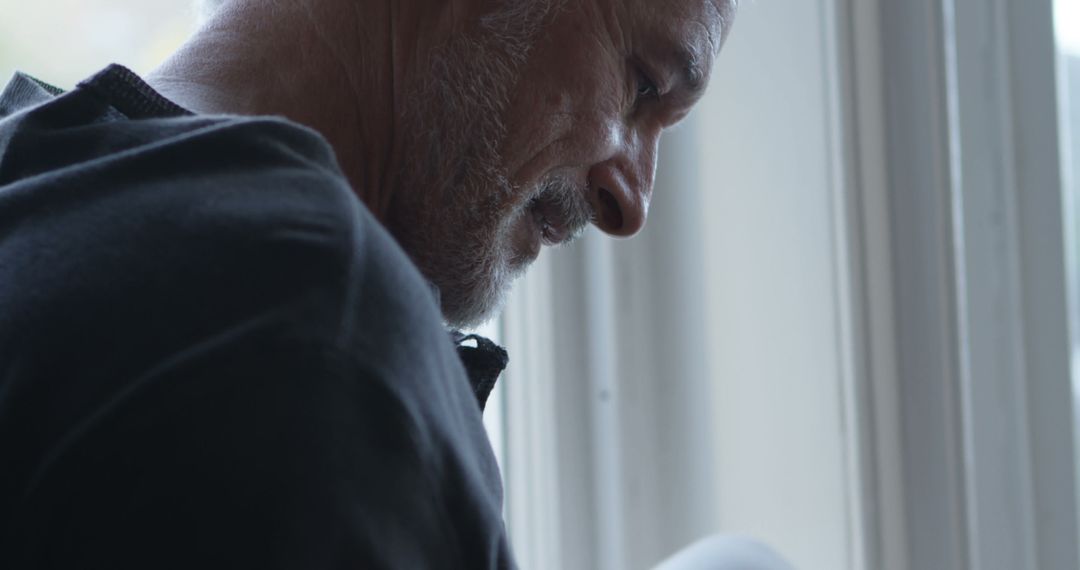 Mature Man in Deep Contemplation Near Sunlit Window - Free Images, Stock Photos and Pictures on Pikwizard.com