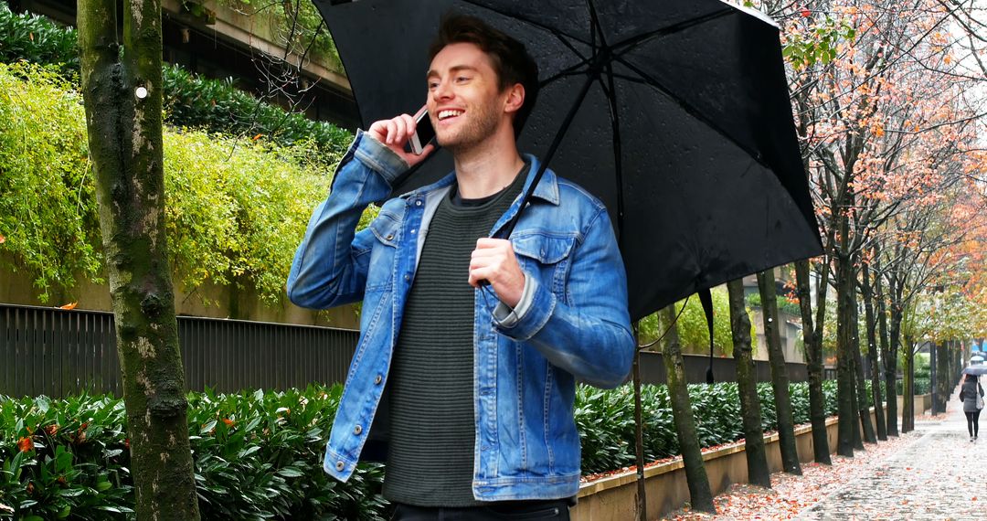 Man Smiling While Talking on Phone with Umbrella in City Street on Rainy Day - Free Images, Stock Photos and Pictures on Pikwizard.com