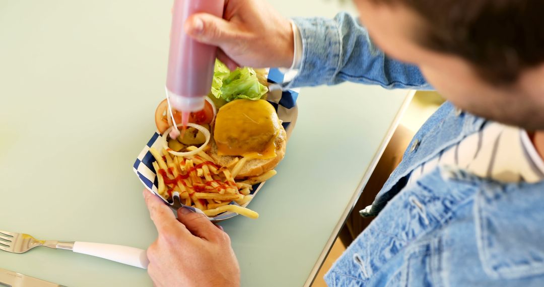 Person Adding Ketchup to Fries with Cheeseburger at Diner - Free Images, Stock Photos and Pictures on Pikwizard.com