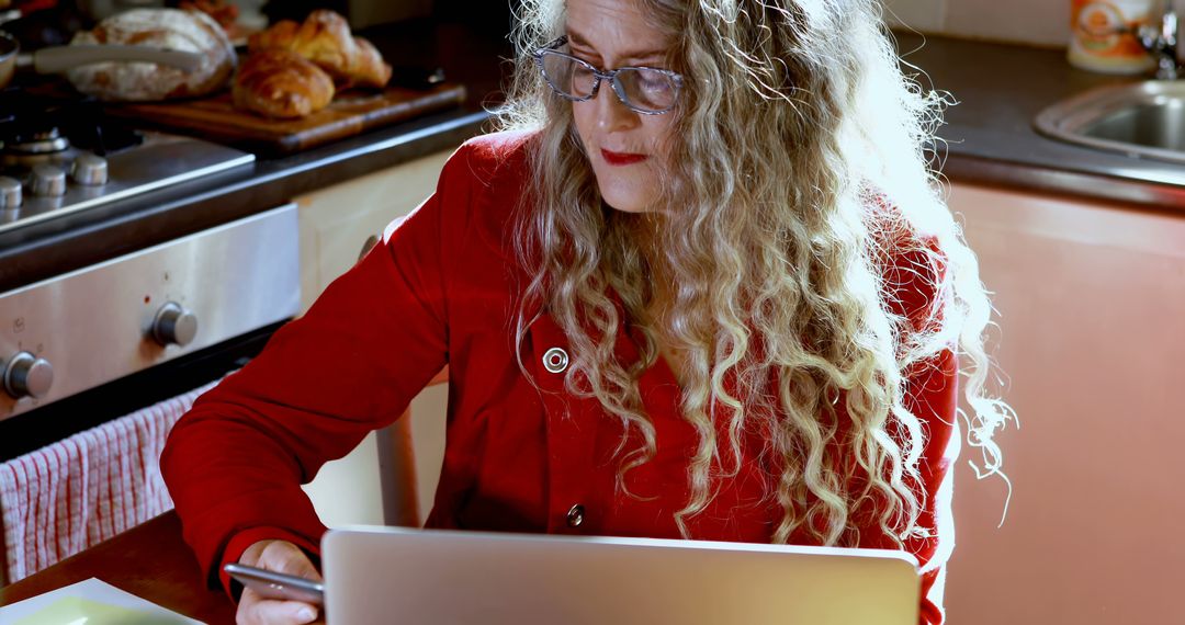 Woman with curly hair working from home on laptop in kitchen - Free Images, Stock Photos and Pictures on Pikwizard.com