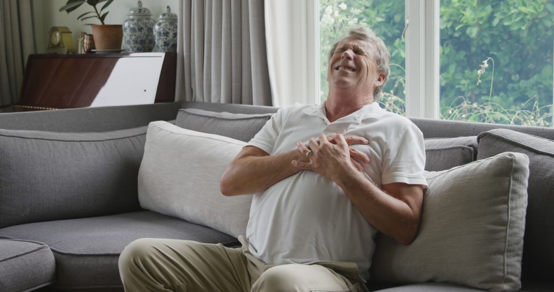 Mature man experiencing chest pain while sitting at home - Free Images, Stock Photos and Pictures on Pikwizard.com