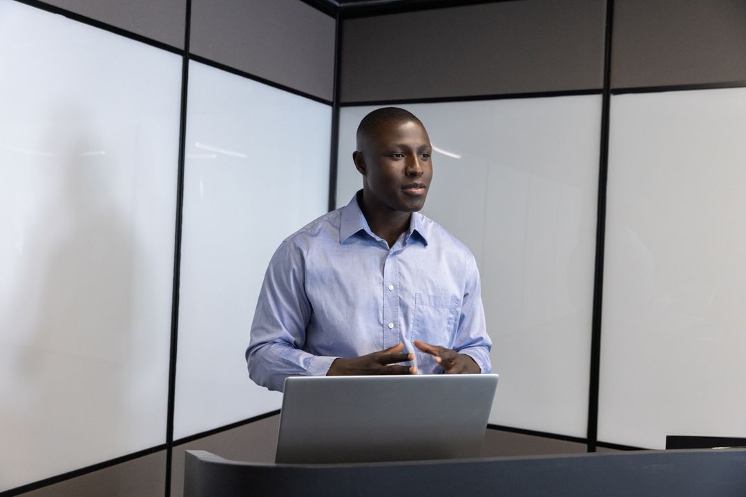 Confident Speaker Presenting in Modern Office with Laptop