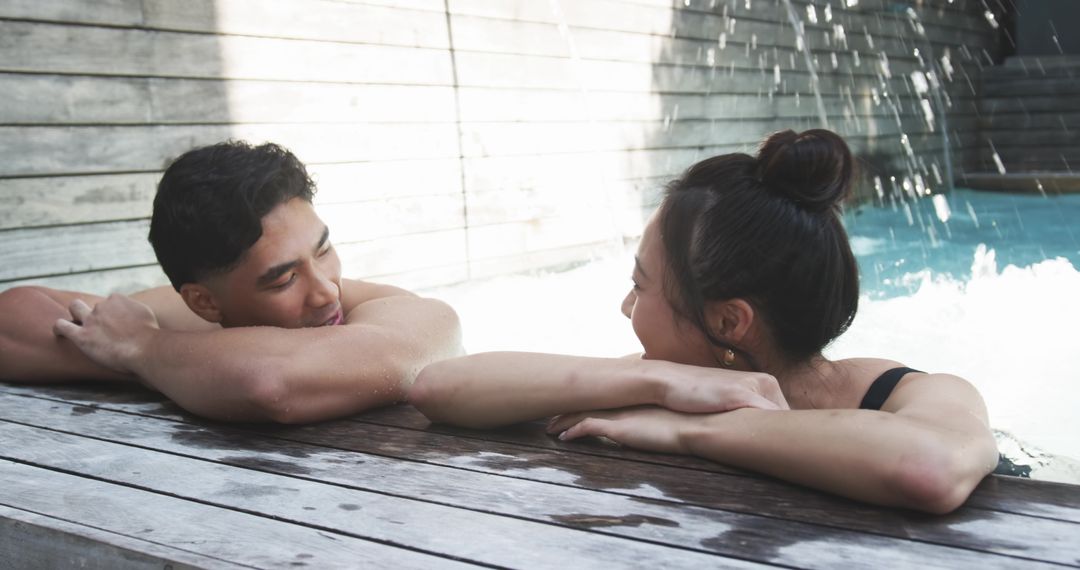 Sunlit couple relaxing at private pool deck with fountain, intimate resort lifestyle