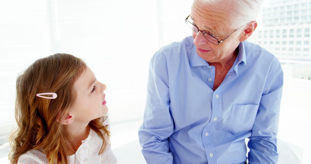 Grandfather Talking With Granddaughter in Bright Room - Free Images, Stock Photos and Pictures on Pikwizard.com