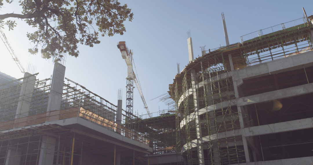 Transparent view of urban construction site with cranes under clear sky