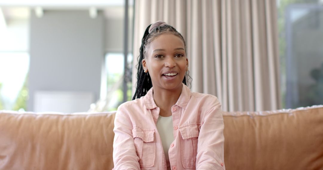 Young Woman with Braided Hair Relaxing on Couch in Bright Living Room