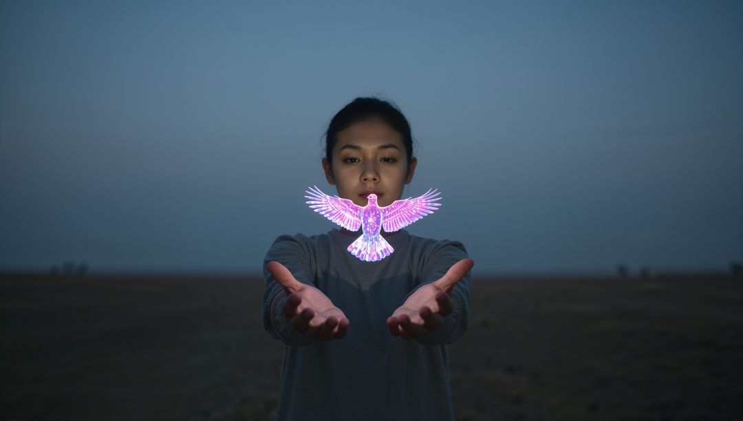 Asian woman holding glowing holographic bird at twilight in open field, neon magic
