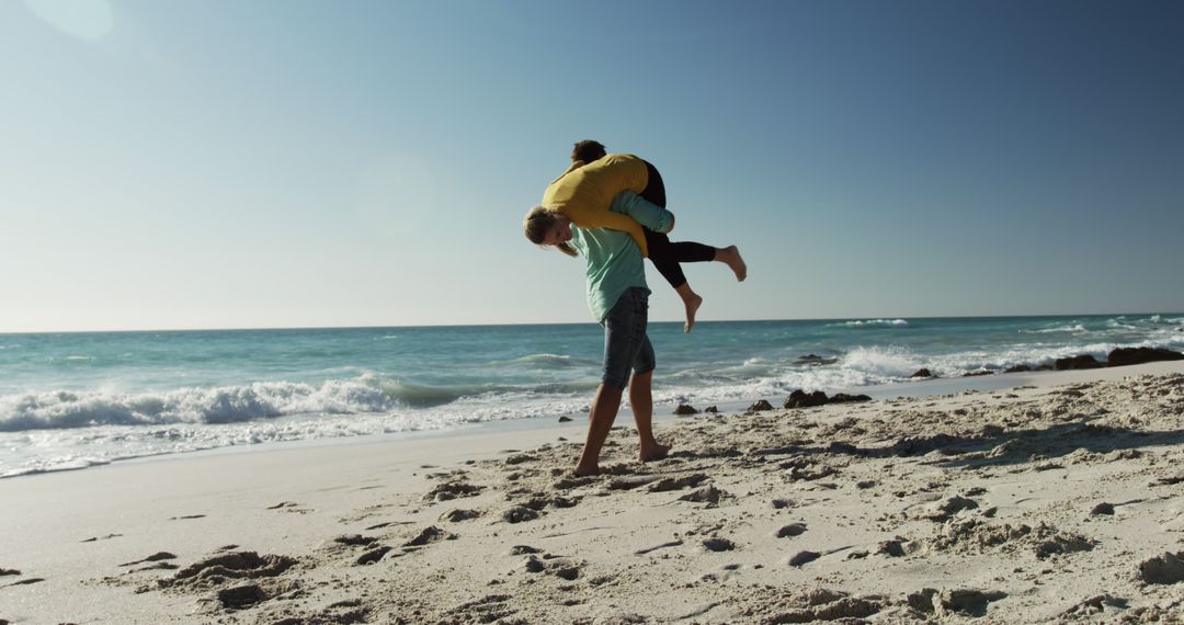 Couple playing together on sandy beach under clear blue sky - Free Images, Stock Photos and Pictures on Pikwizard.com