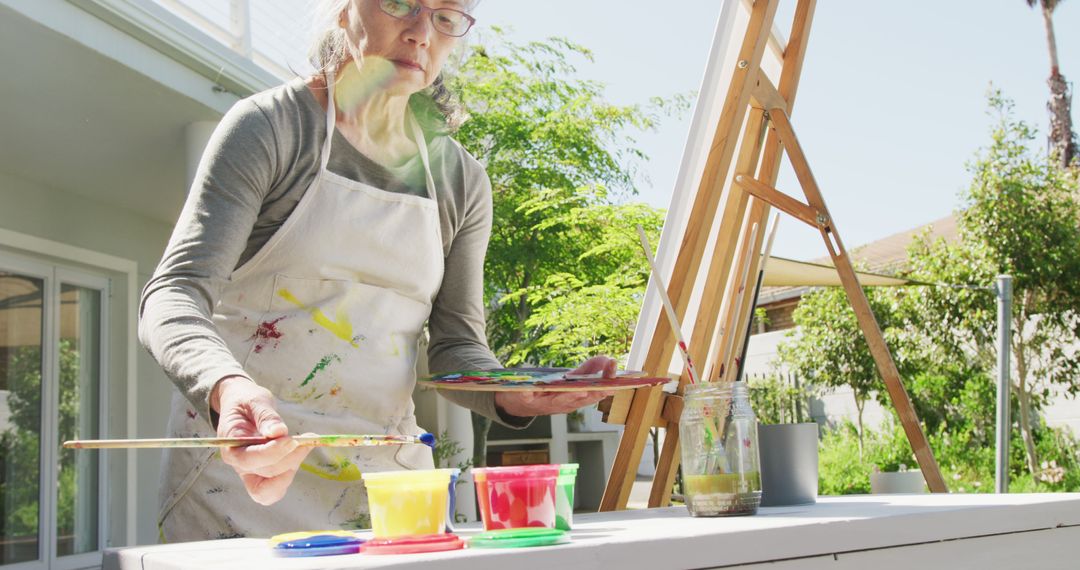 Senior Woman Painting on Easel in Outdoor Garden - Free Images, Stock Photos and Pictures on Pikwizard.com