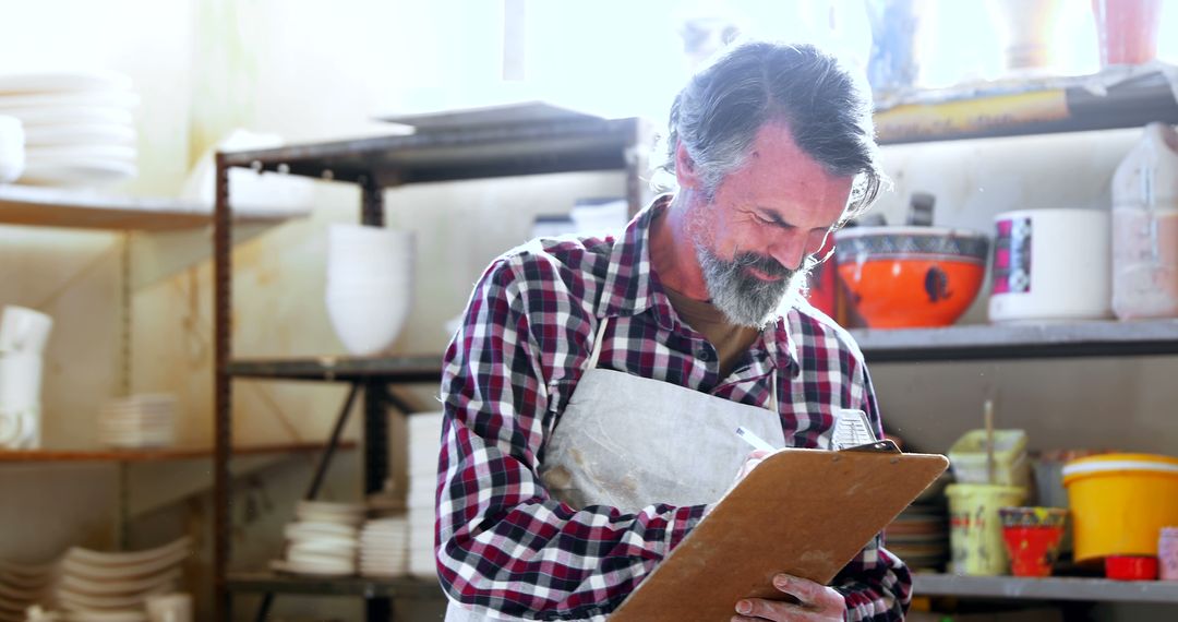 Smiling Middle-aged Man in Pottery Workshop Holding Clipboard - Free Images, Stock Photos and Pictures on Pikwizard.com