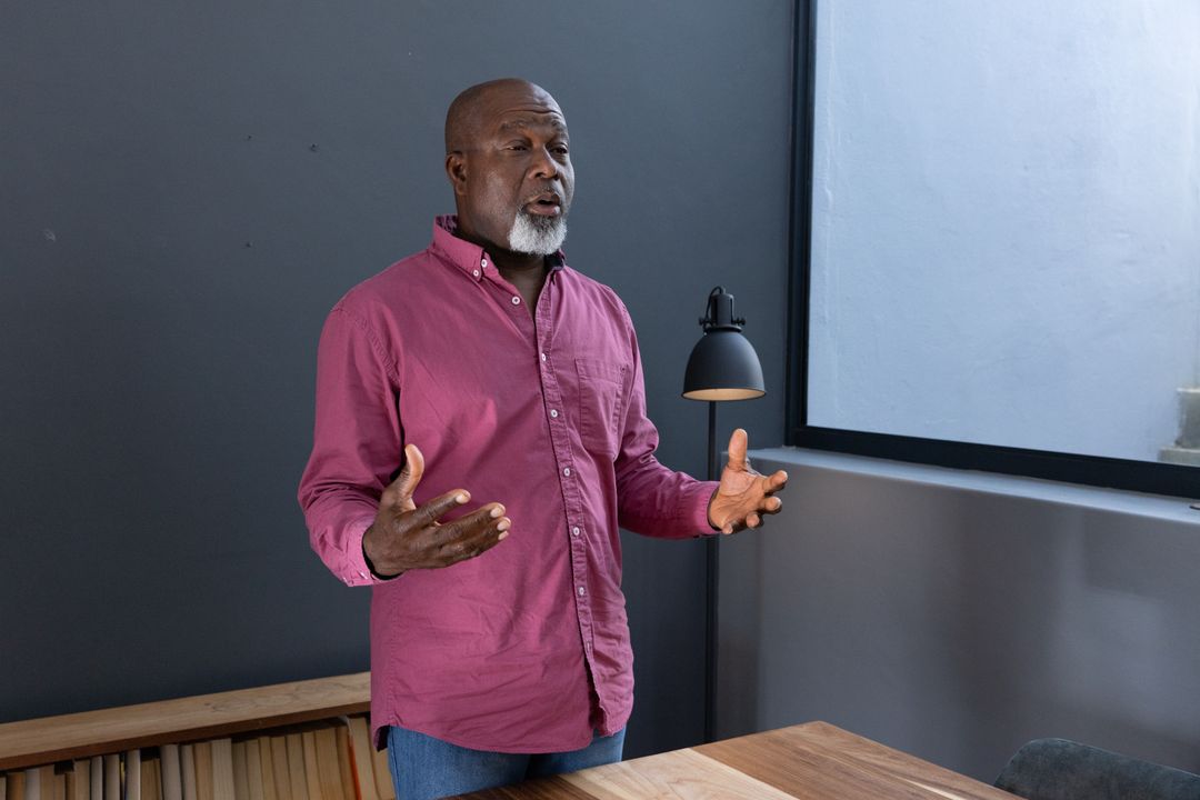 Senior Man Gesturing While Presenting in Modern Office