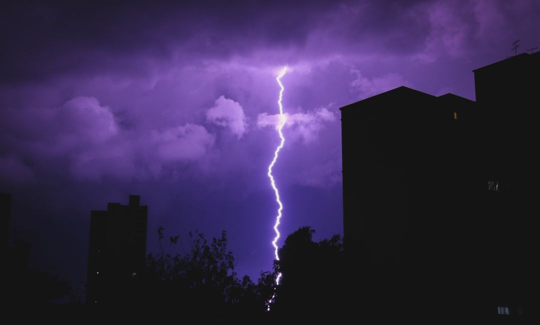 Dramatic purple lightning striking night cityscape silhouette - Free Images, Stock Photos and Pictures on Pikwizard.com