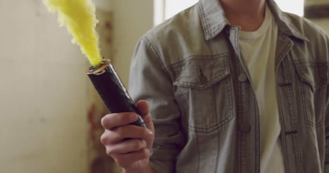 Young biracial man holding a lit smoke flare indoors - Free Images, Stock Photos and Pictures on Pikwizard.com