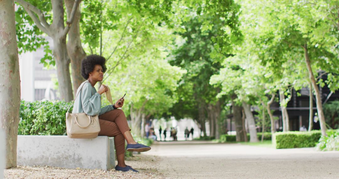 Woman Using Smartphone and Enjoying Snack in Park