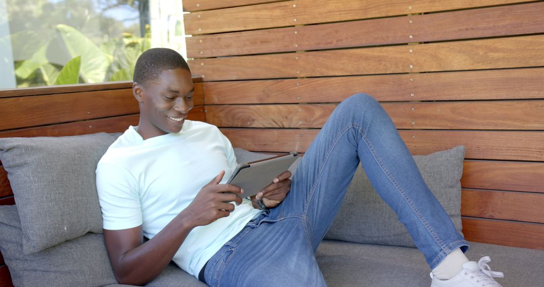 Man Relaxing on Couch Using Tablet for Leisure Entertainment