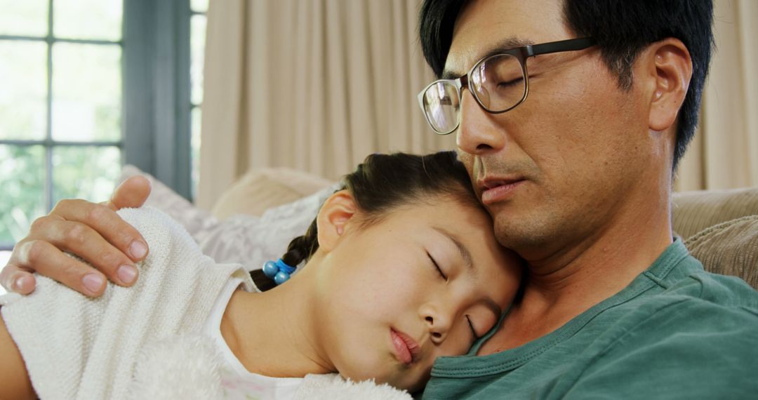 Father Holding Sleeping Daughter on Couch in Sunlit Room - Free Images, Stock Photos and Pictures on Pikwizard.com