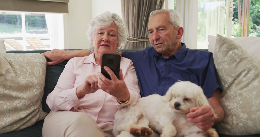 Elderly Couple Relaxing on Couch Using Smartphone with Small Dog - Free Images, Stock Photos and Pictures on Pikwizard.com