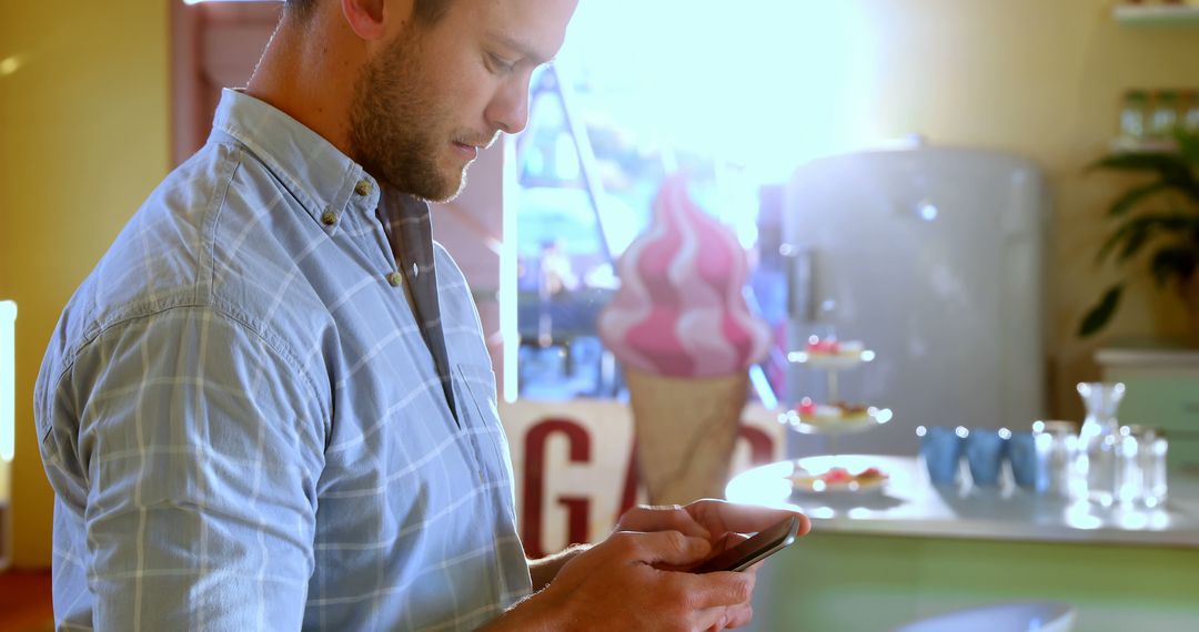 Man Using Smartphone in Bright Ice Cream Shop - Free Images, Stock Photos and Pictures on Pikwizard.com