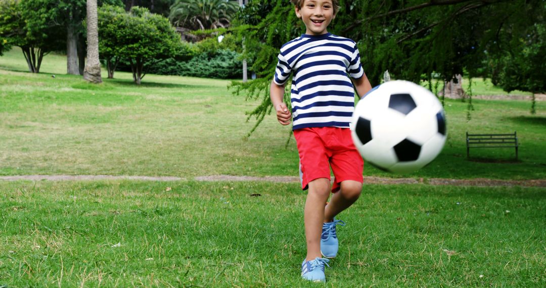 Smiling Boy Kicking Soccer Ball in Park on Sunny Day - Free Images, Stock Photos and Pictures on Pikwizard.com