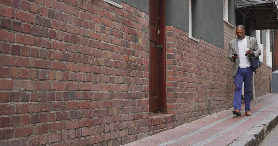 Stylish Man Walking along Brick Pathway on Urban Street - Free Images, Stock Photos and Pictures on Pikwizard.com