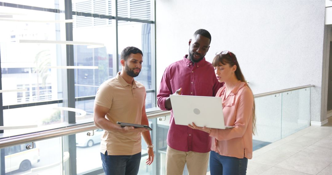 Diverse Team Collaborating with Technology in Office Hallway