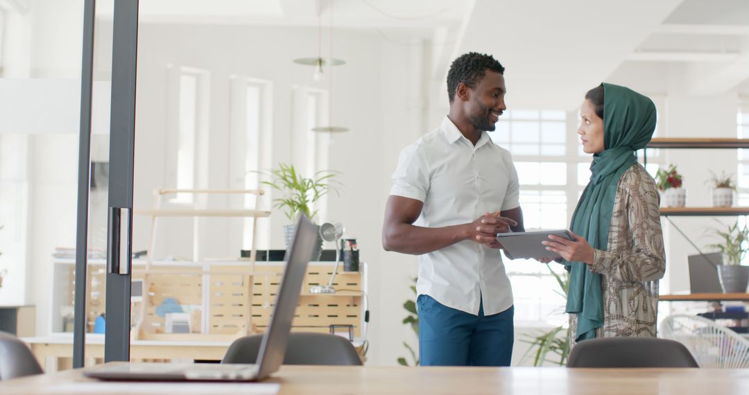 Diverse Colleagues Engaging in Office Discussion with Tablet