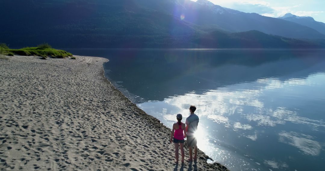 Couple Enjoying Scenic Beach Walk by Calm Lake - Free Images, Stock Photos and Pictures on Pikwizard.com