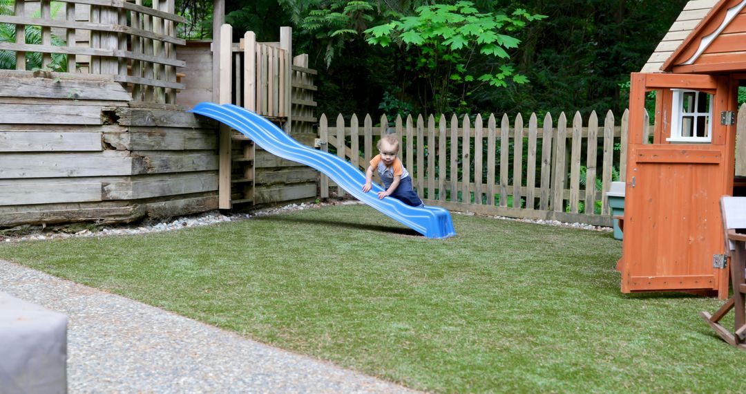 Toddler playing on blue slide in backyard - Free Images, Stock Photos and Pictures on Pikwizard.com