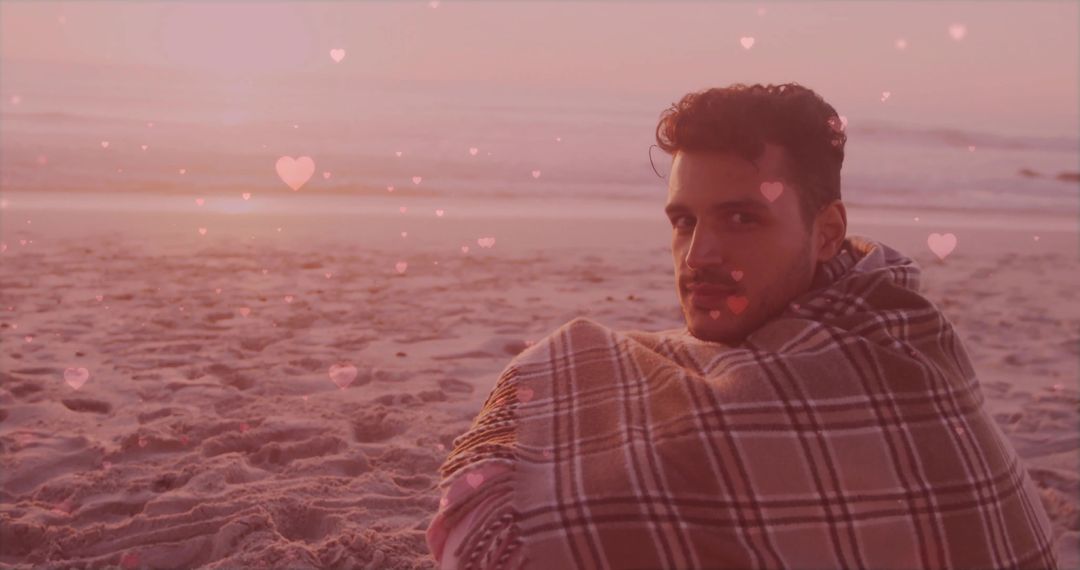 Man Wrapped in Plaid Blanket on Sandy Beach at Sunset