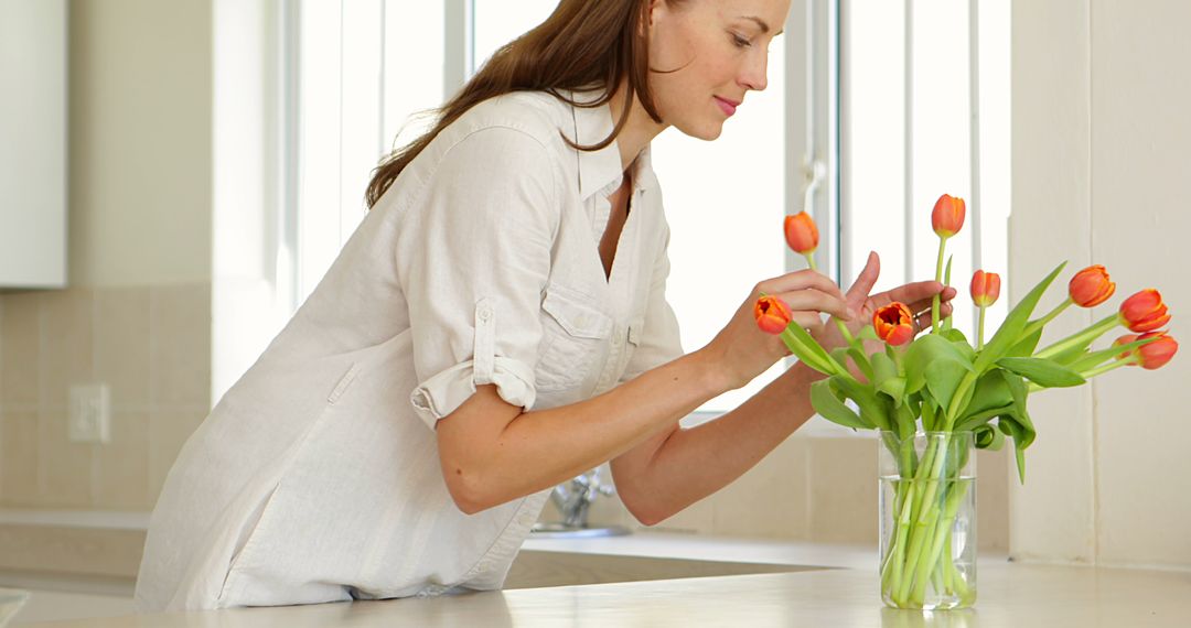 Woman Arranging Tulips in Modern Kitchen with Natural Light - Free Images, Stock Photos and Pictures on Pikwizard.com