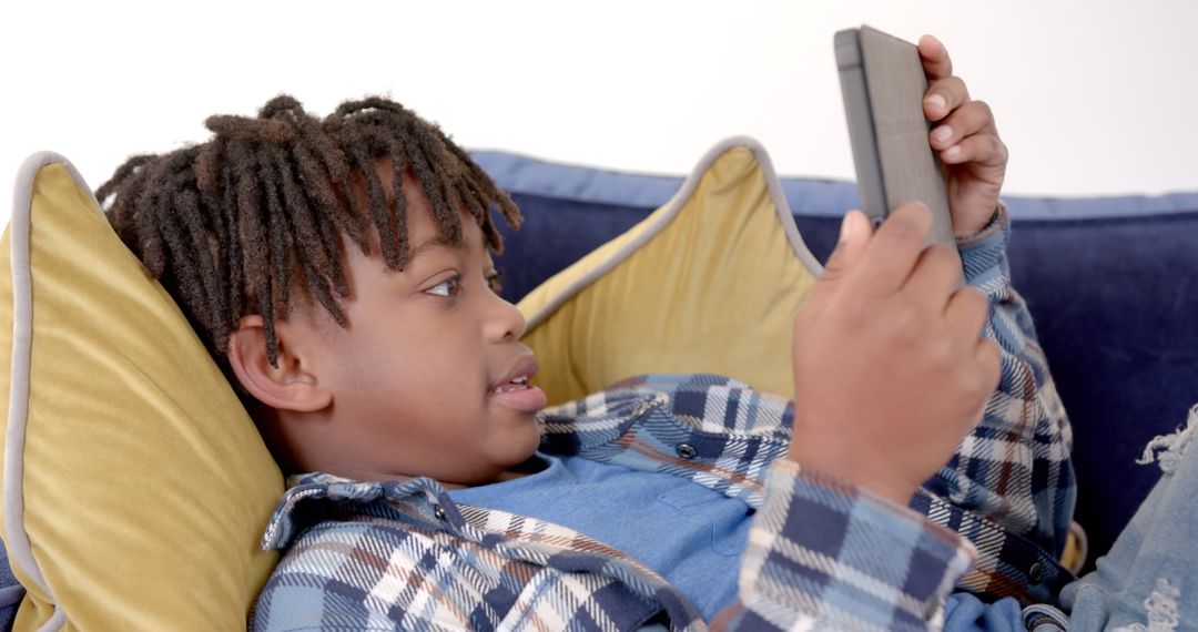 African American Boy Relaxing with Tablet on Sofa at Home