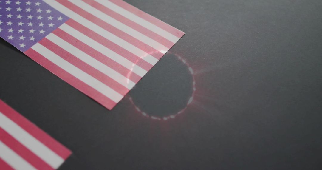 American flag corner reflecting circular lens flare on dark tabletop with glossy stripes
