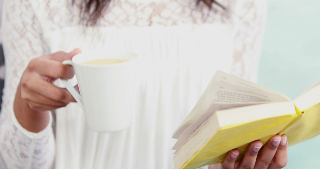 Woman Reading Book While Holding Cup of Coffee - Free Images, Stock Photos and Pictures on Pikwizard.com